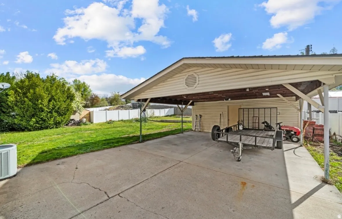 Covered carport with concrete flooring and beige vinyl siding