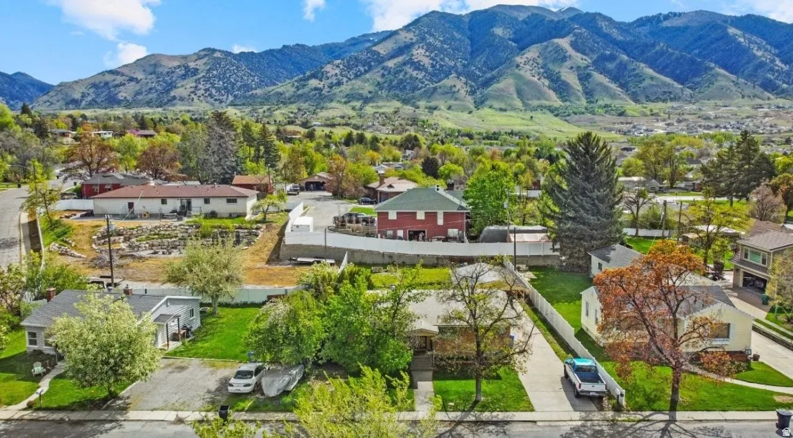 Expansive property featuring a paved driveway, mature trees, and a surrounding mountain backdrop