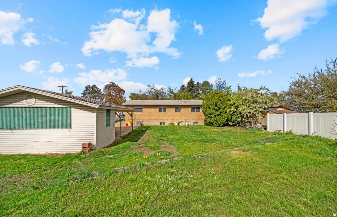 Expansive grassy yard area with a detached outbuilding and a vinyl privacy fence