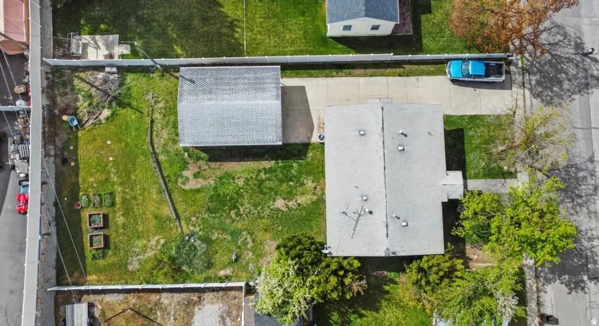 Expansive lot featuring a primary structure with a gray shingle roof, a detached garage with a gray shingle roof, a concrete driveway, and a large grassy area