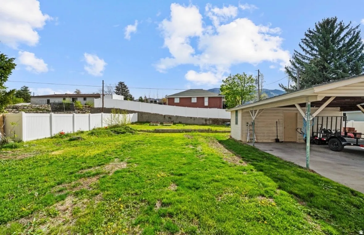Expansive grassy yard with a white privacy fence