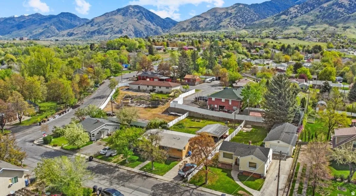 Residential neighborhood with established homes, mature trees, paved streets, and mountainous terrain in the background