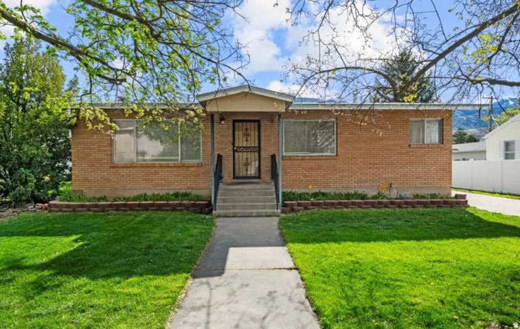 Brick exterior residence featuring a covered front entry, concrete walkway, and established front yard