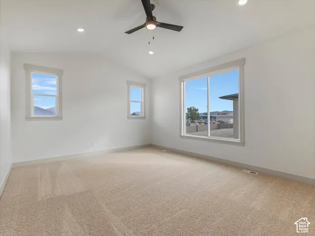 Vaulted ceiling with a ceiling fan, recessed lighting, expansive windows, and plush carpeting