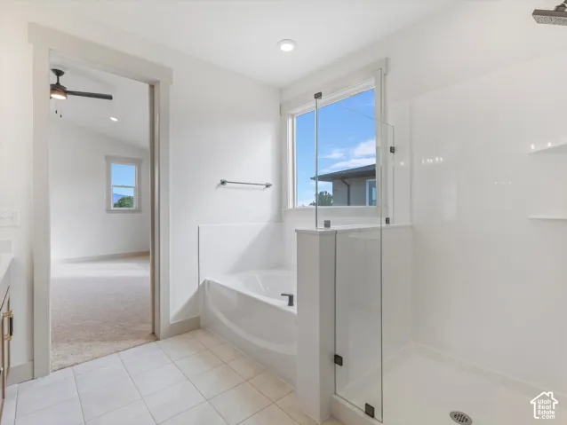 Tiled flooring, built-in soaking tub, glass-enclosed shower, window with exterior scenery, and recessed lighting