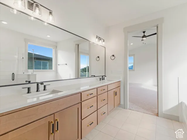 Dual vanity with light wood-finish cabinetry, matte black hardware, and an expansive mirror