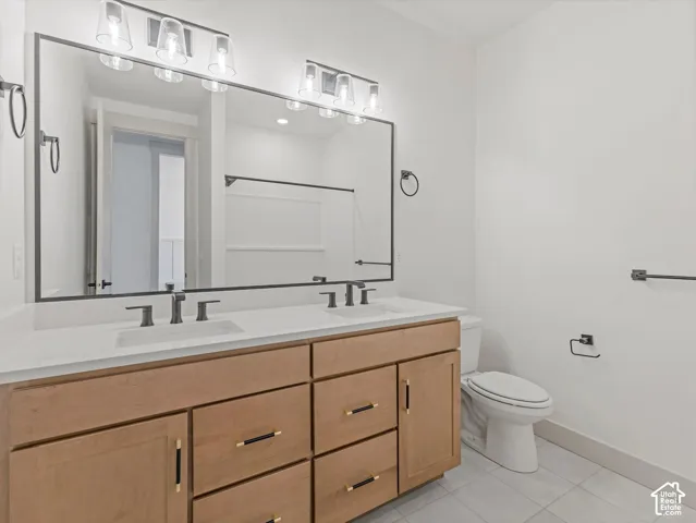 Double vanity with light wood-finish cabinetry, white countertop, and matte black hardware