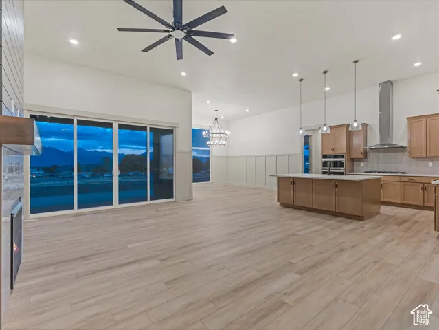 Spacious open-concept living area featuring wood-finish flooring, a contemporary ceiling fan, and recessed lighting