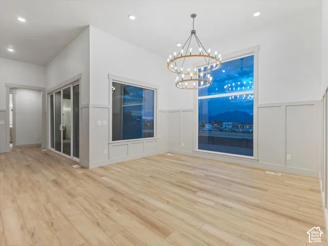 Expansive interior featuring high ceilings, wood-finish flooring, a two-tier chandelier, wainscoting, and large windows