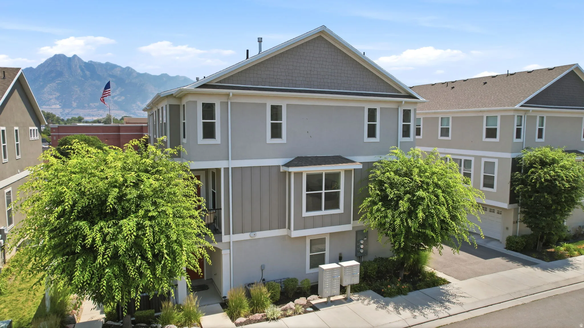Modern townhome exterior featuring light gray siding, dark gray board and batten accents, and a contrasting dark shingle roof