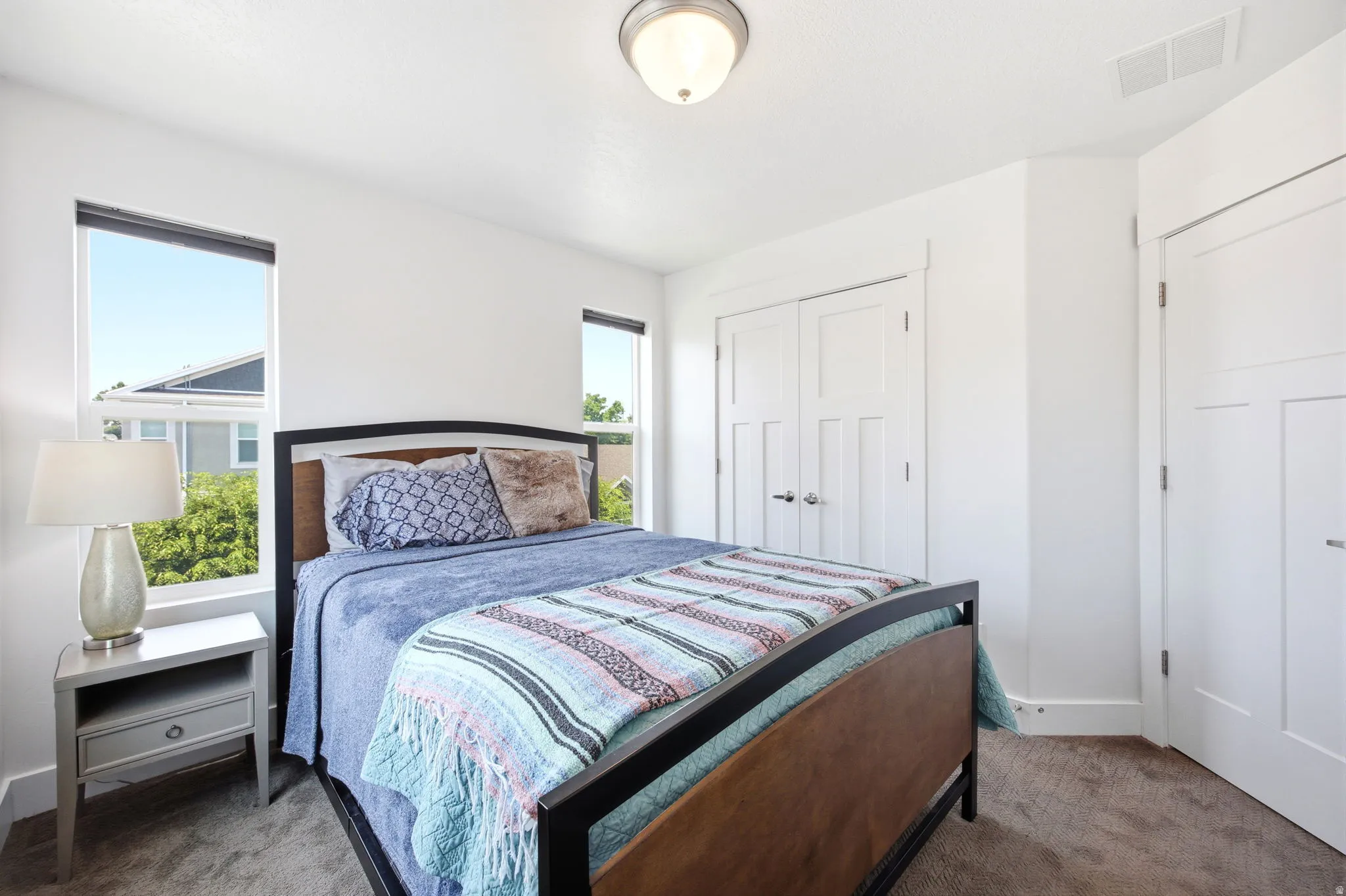 Bedroom featuring neutral wall colors, two windows, two panel doors, and carpet flooring