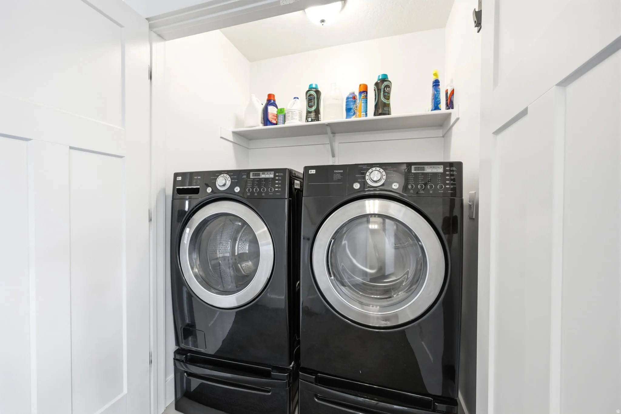 Dedicated laundry area featuring a stacked washer and dryer, an overhead shelf, and white paneled doors