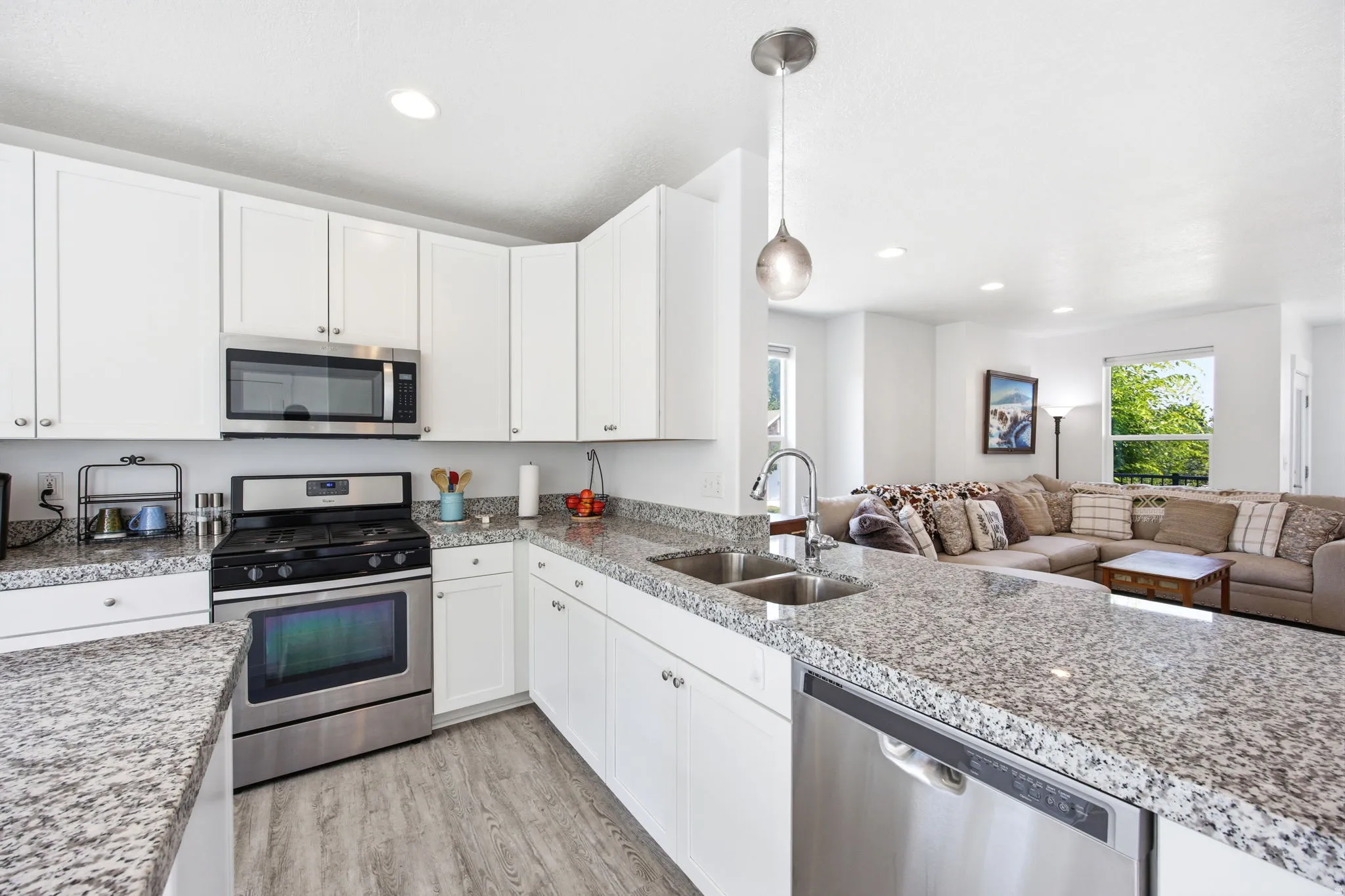 Kitchen featuring white cabinetry, stainless steel appliances, speckled stone countertops, and wood-finish flooring