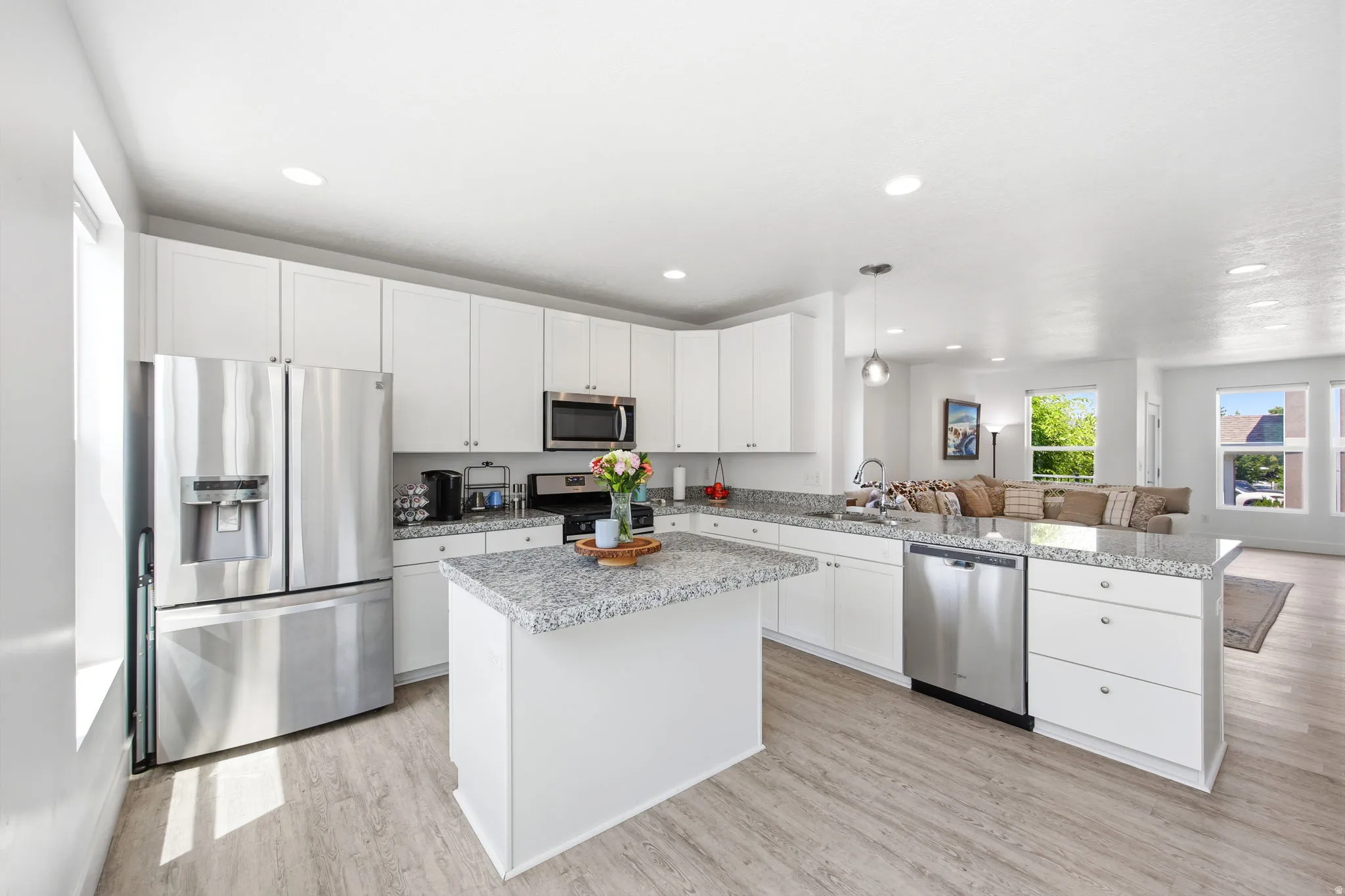 Modern kitchen featuring white cabinetry, stainless steel appliances, a center island with countertop seating, and light wood-finish flooring