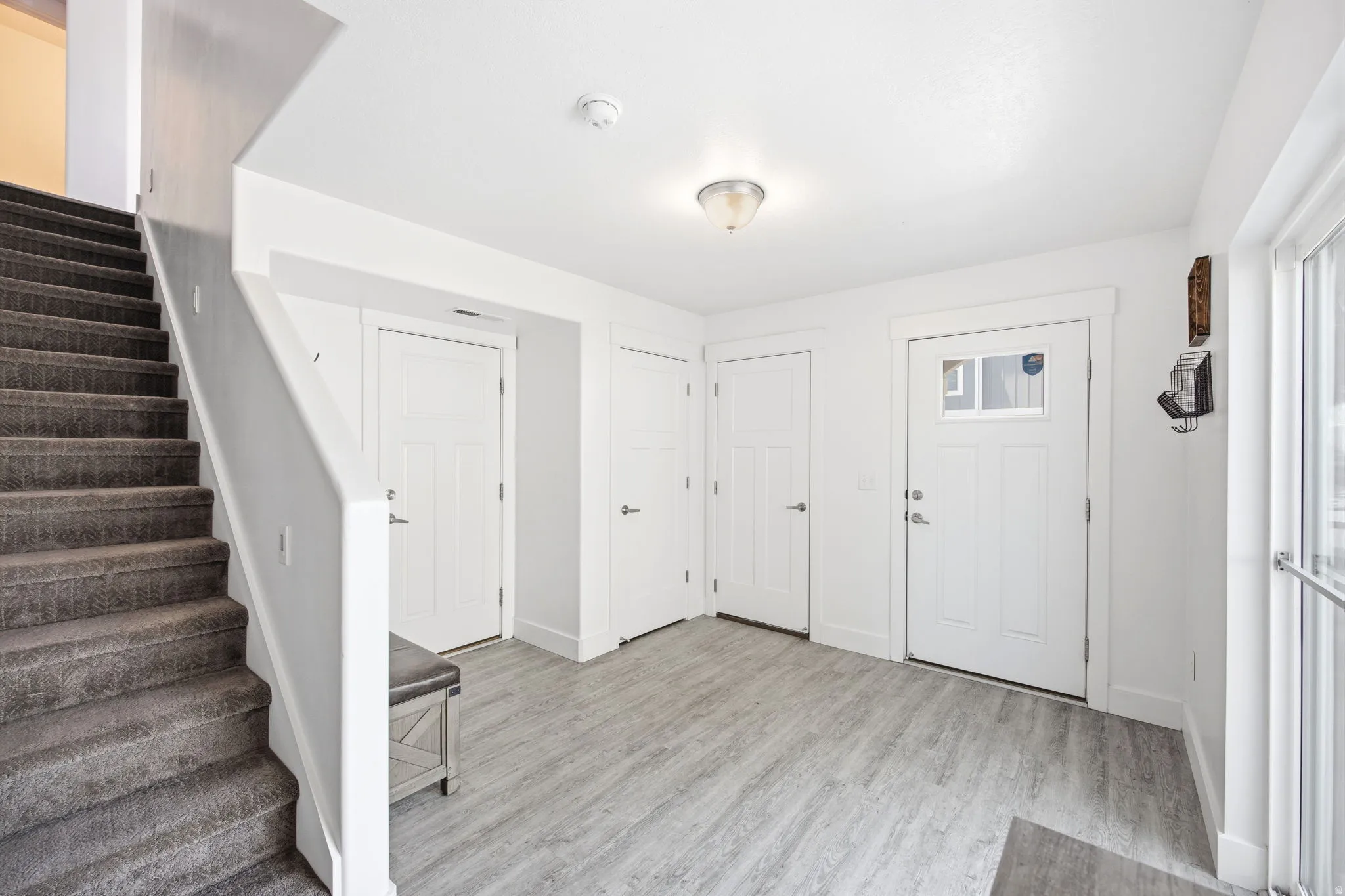 Entry foyer featuring wood-finish flooring and a carpeted staircase