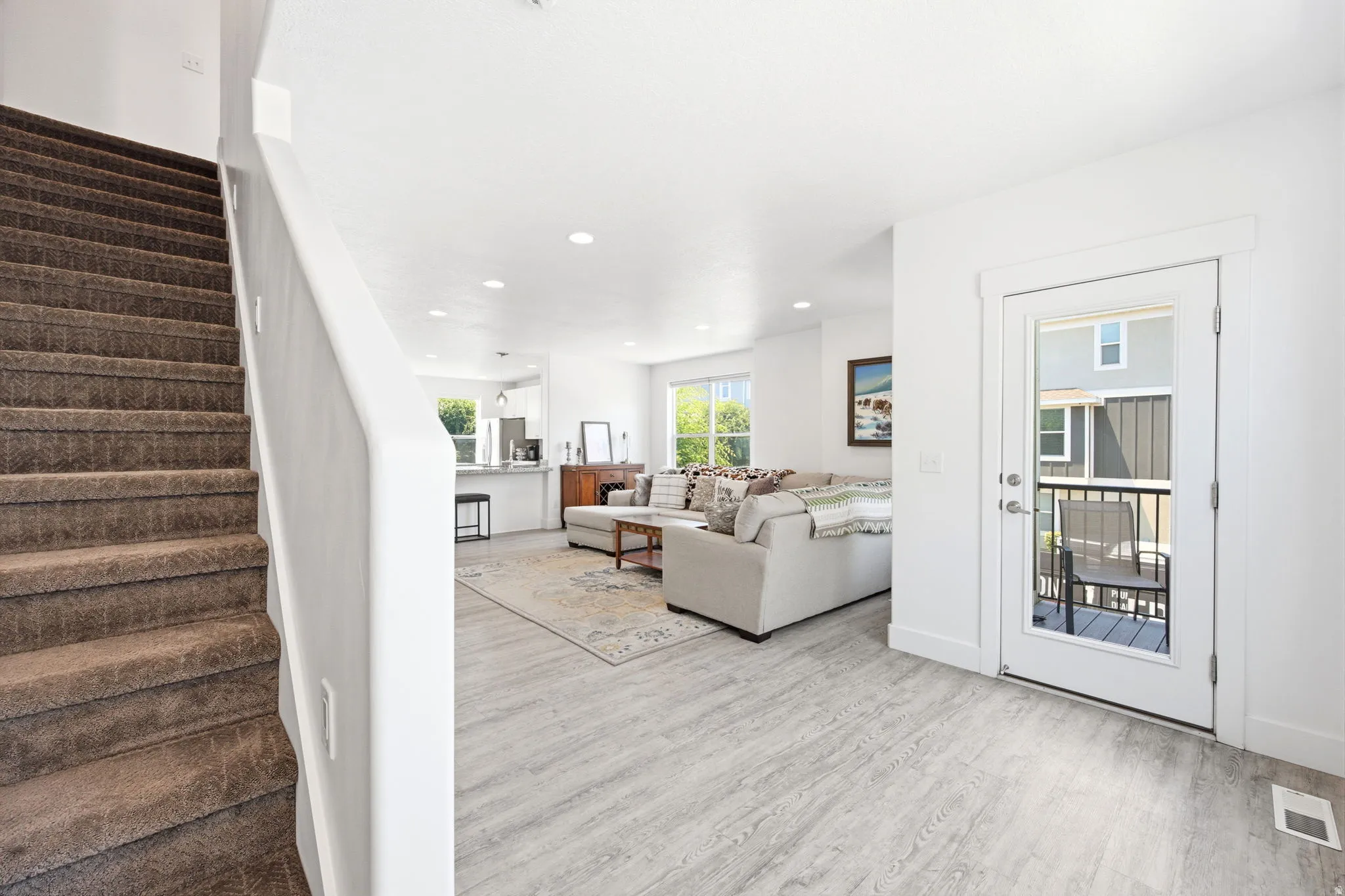 Open-concept living space featuring wood-finish flooring, recessed lighting, and a white interior color palette