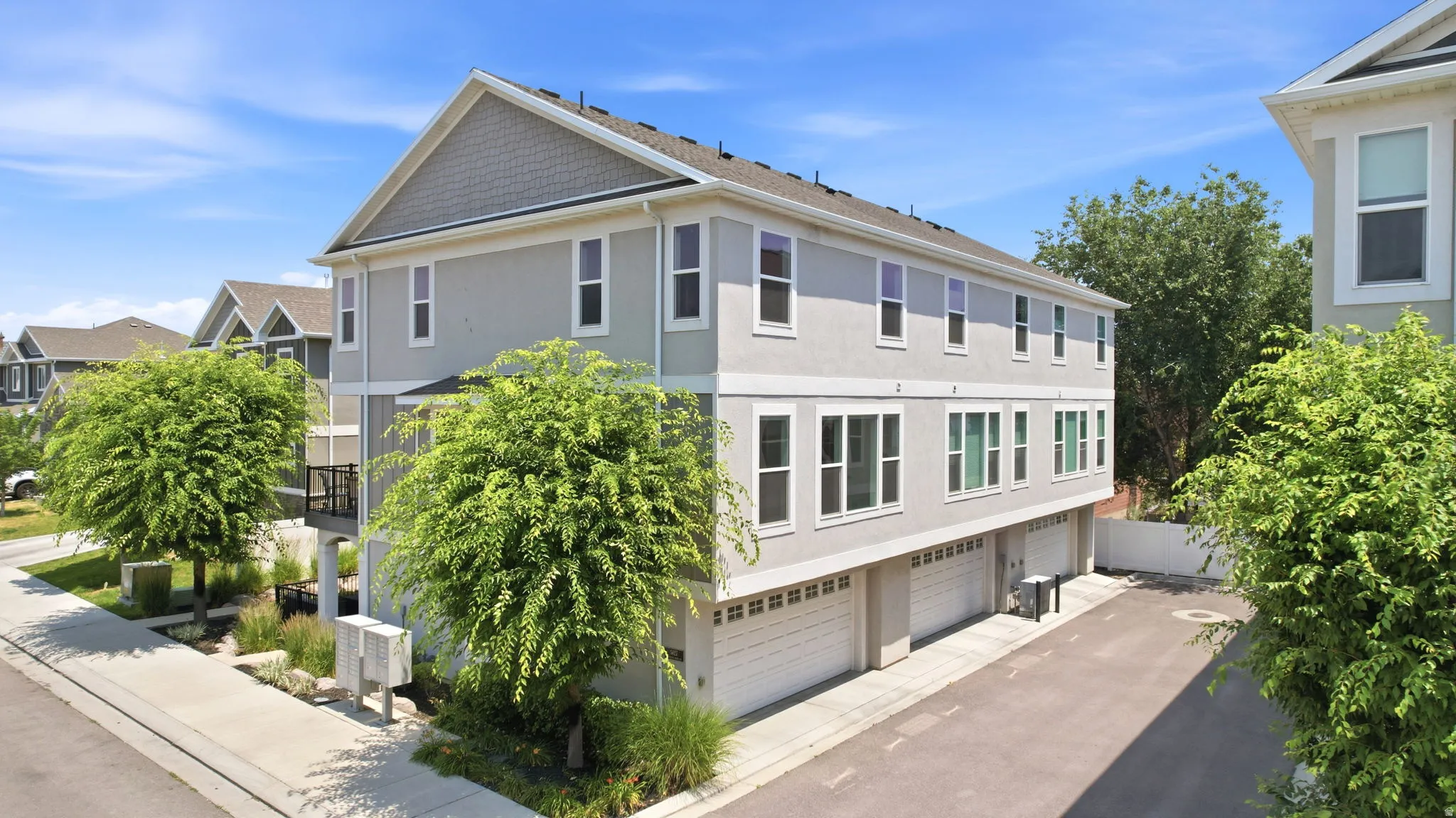 Modern townhome exterior featuring light gray stucco siding and multiple large windows