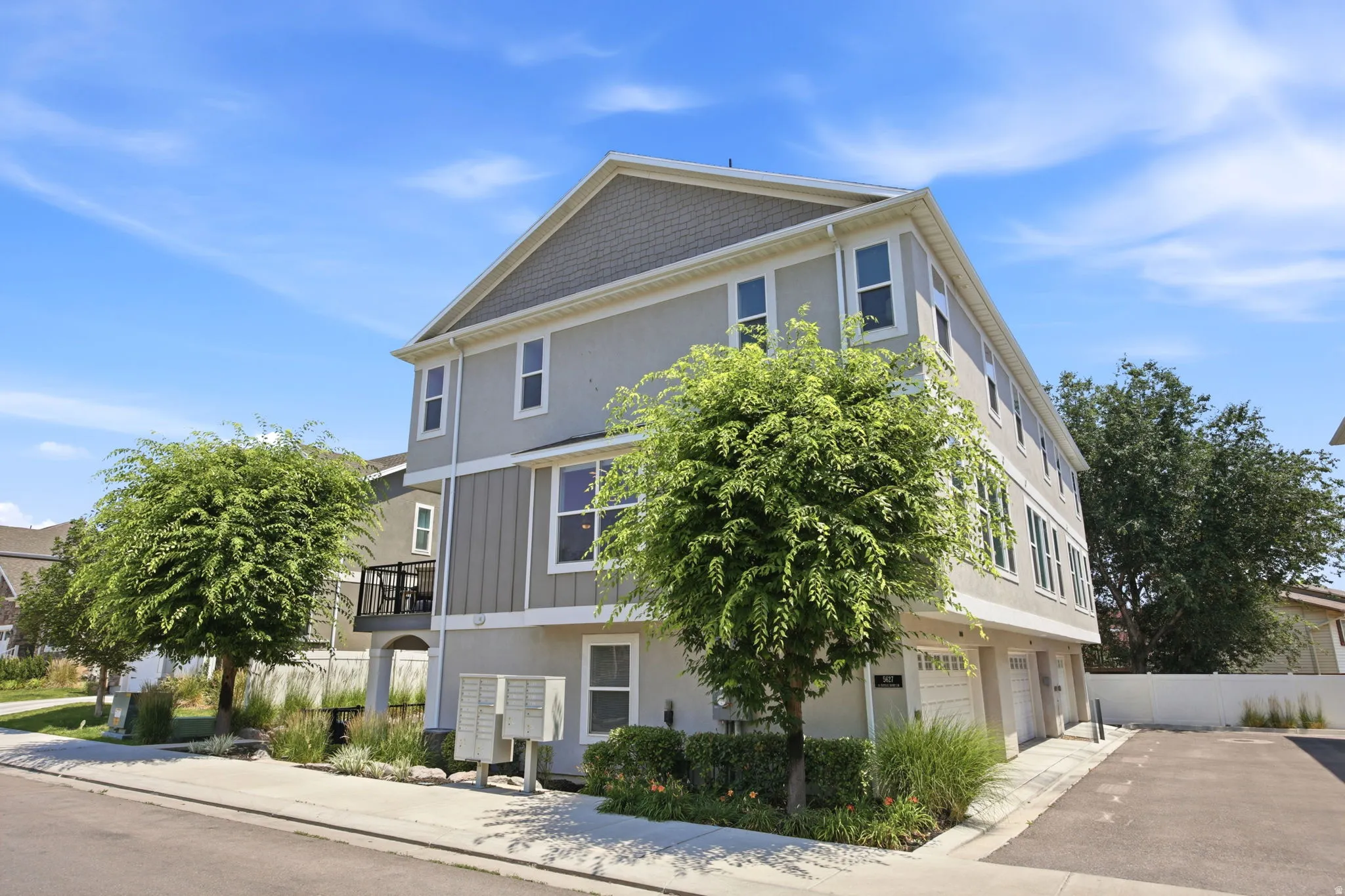 Contemporary multi-story property featuring a stucco exterior with vertical siding accents, multiple windows, and a private balcony