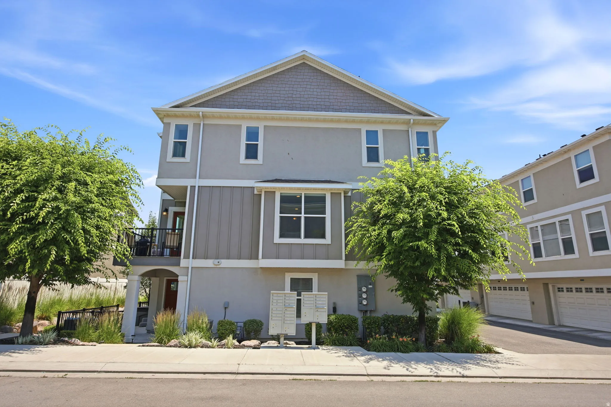 Three-story residence featuring a balcony with black railings, a pitched roofline, and multiple windows