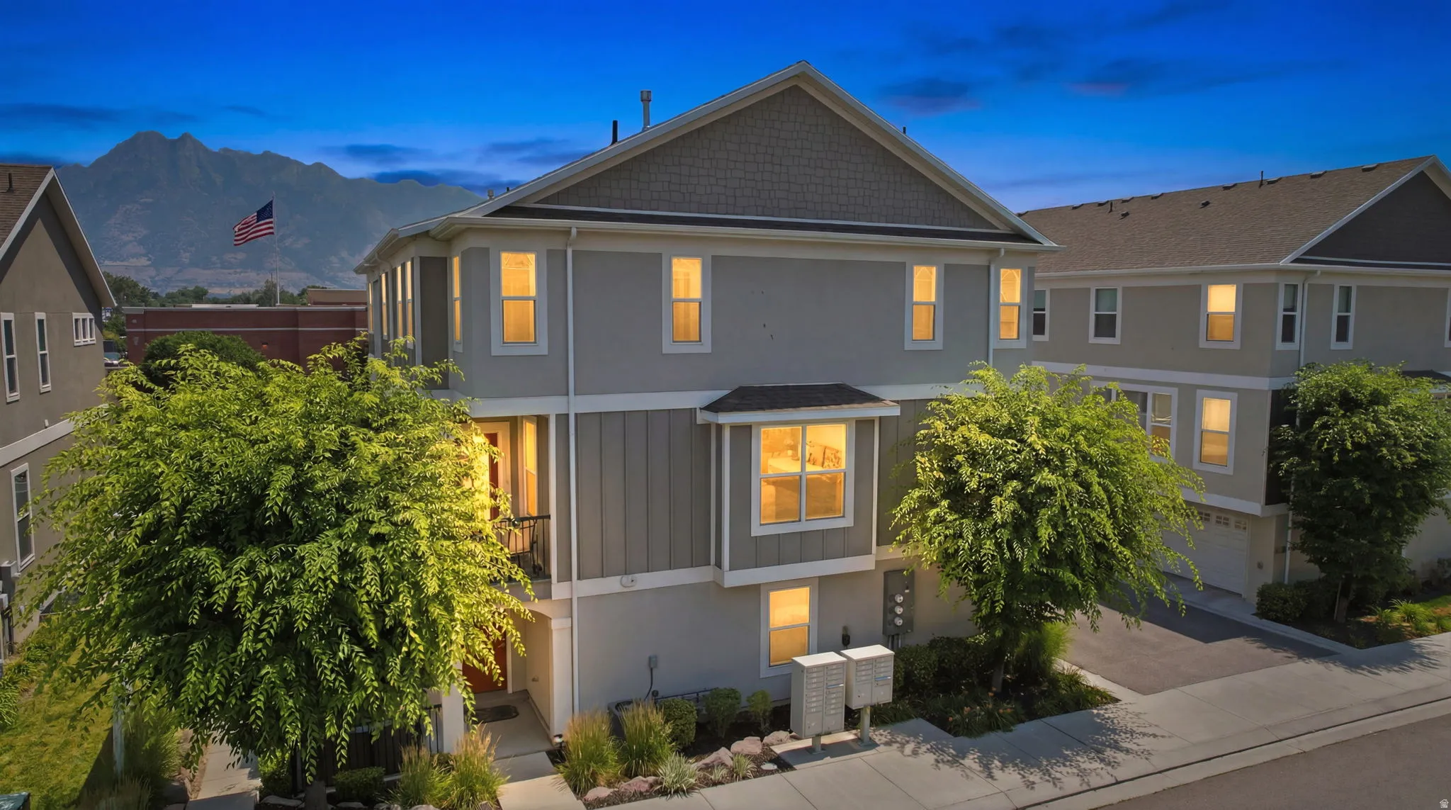 Modern multi-level residence featuring gray siding with vertical wood-finish accents