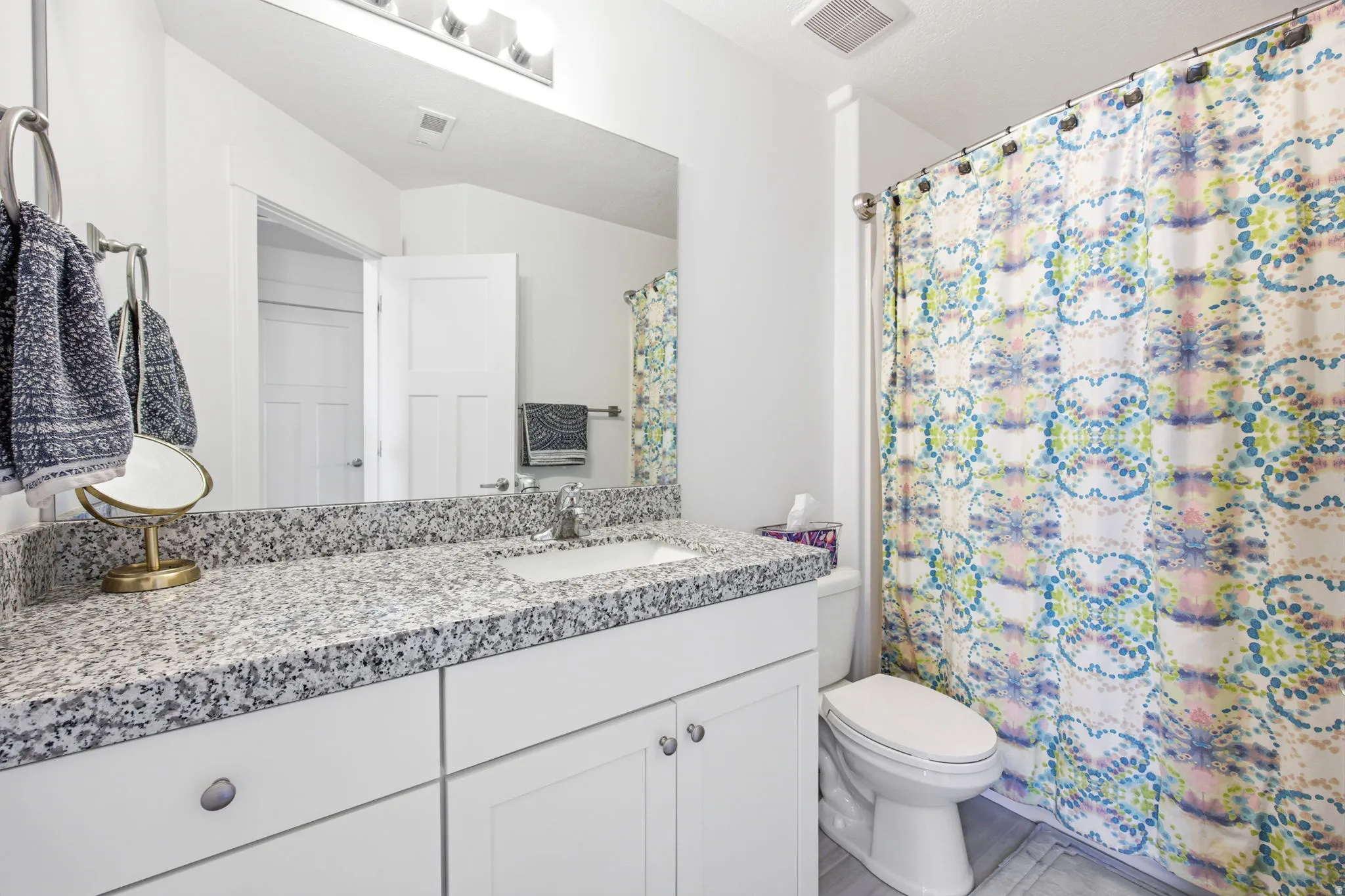 Bathroom featuring a white vanity with recessed panel cabinetry, a speckled stone countertop, and an undermount sink