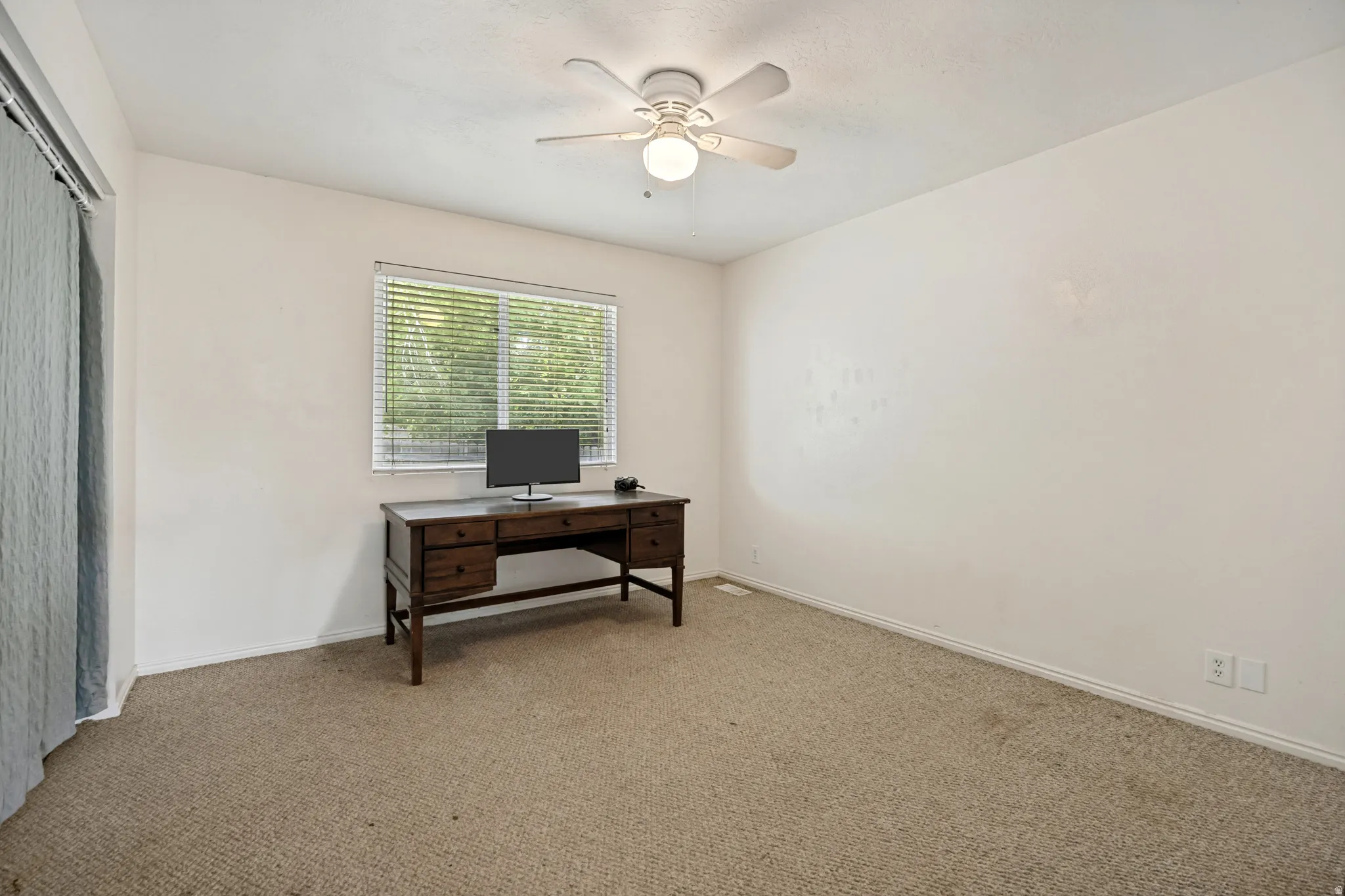 Carpeted room featuring a window with horizontal blinds, a white ceiling fan with integrated lighting, and light-toned walls