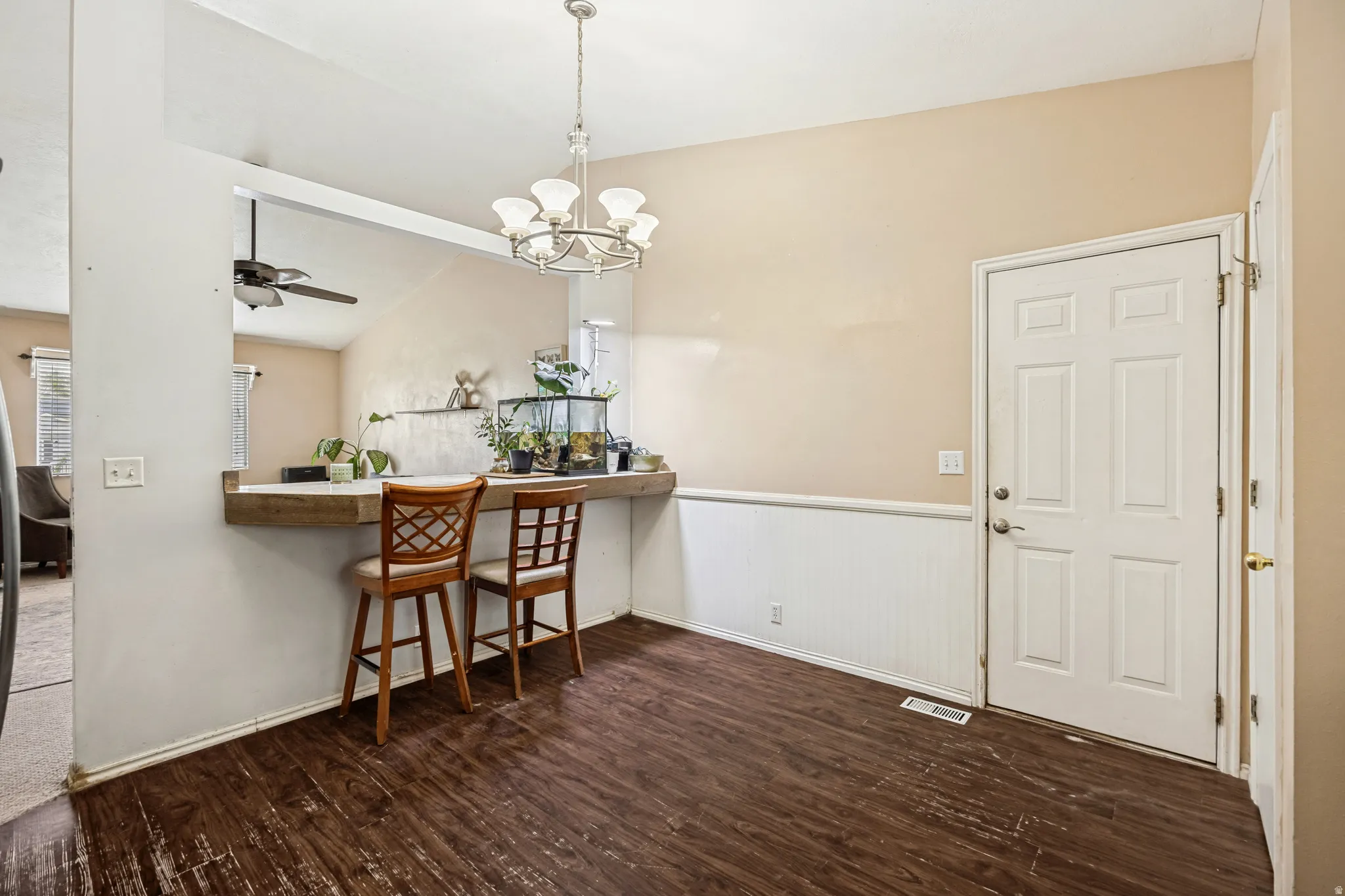 Dining area featuring wood-finish flooring, a white paneled entry door, and a built-in breakfast bar