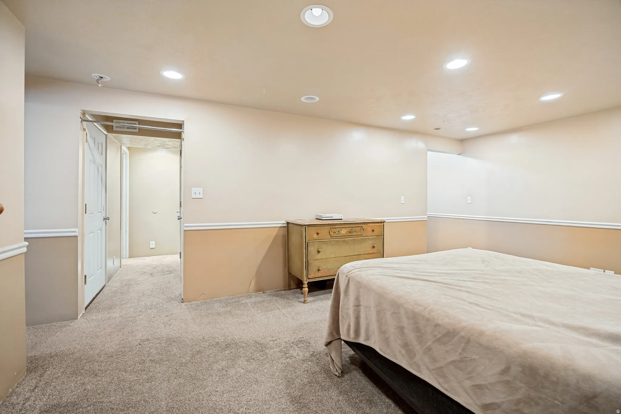 Carpeted room featuring recessed lighting, a two-tone wall treatment with chair rail molding, and a doorway leading to an interior hallway