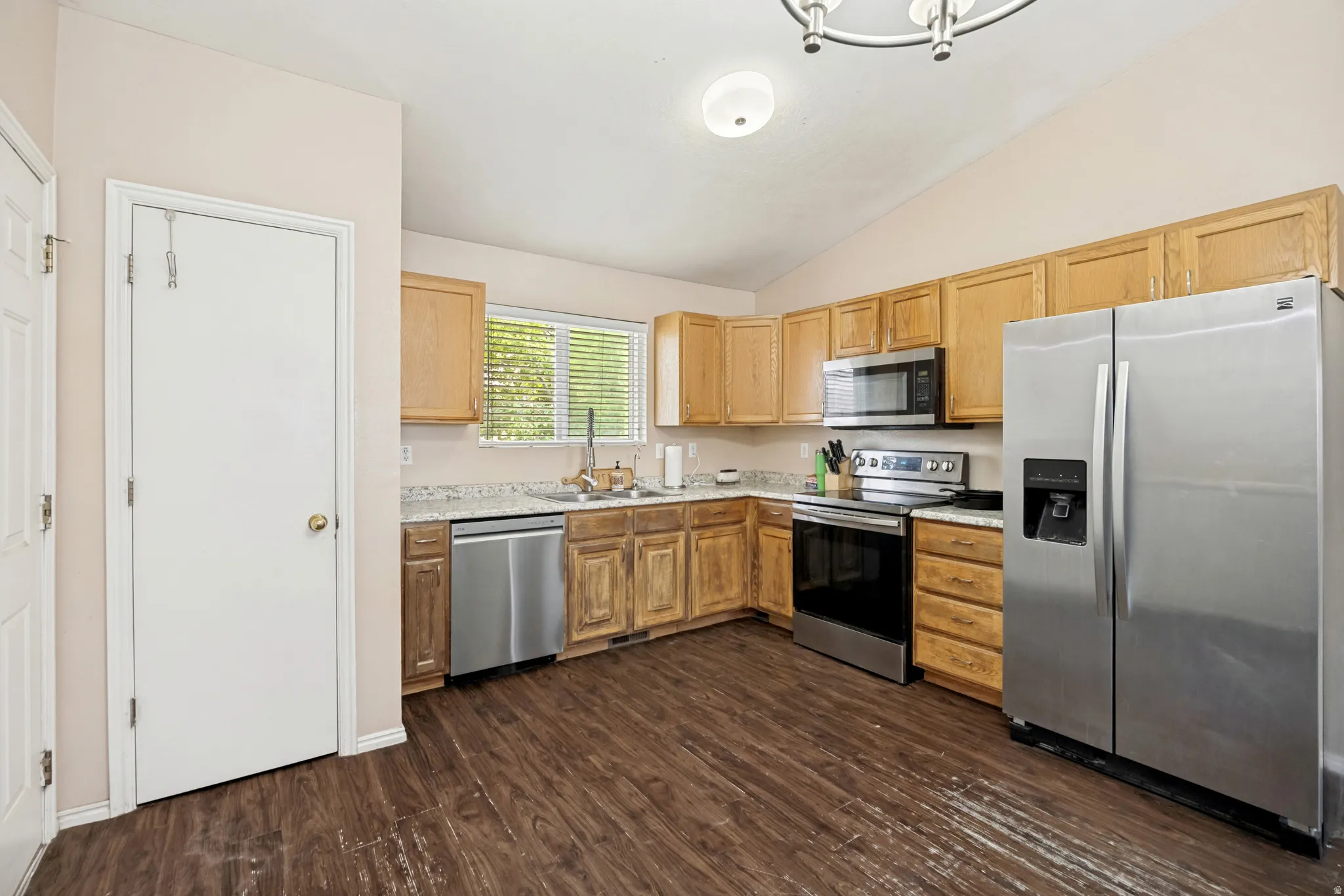 Kitchen featuring wood-finish flooring, light wood cabinetry, stone-finish countertops, and stainless steel appliances