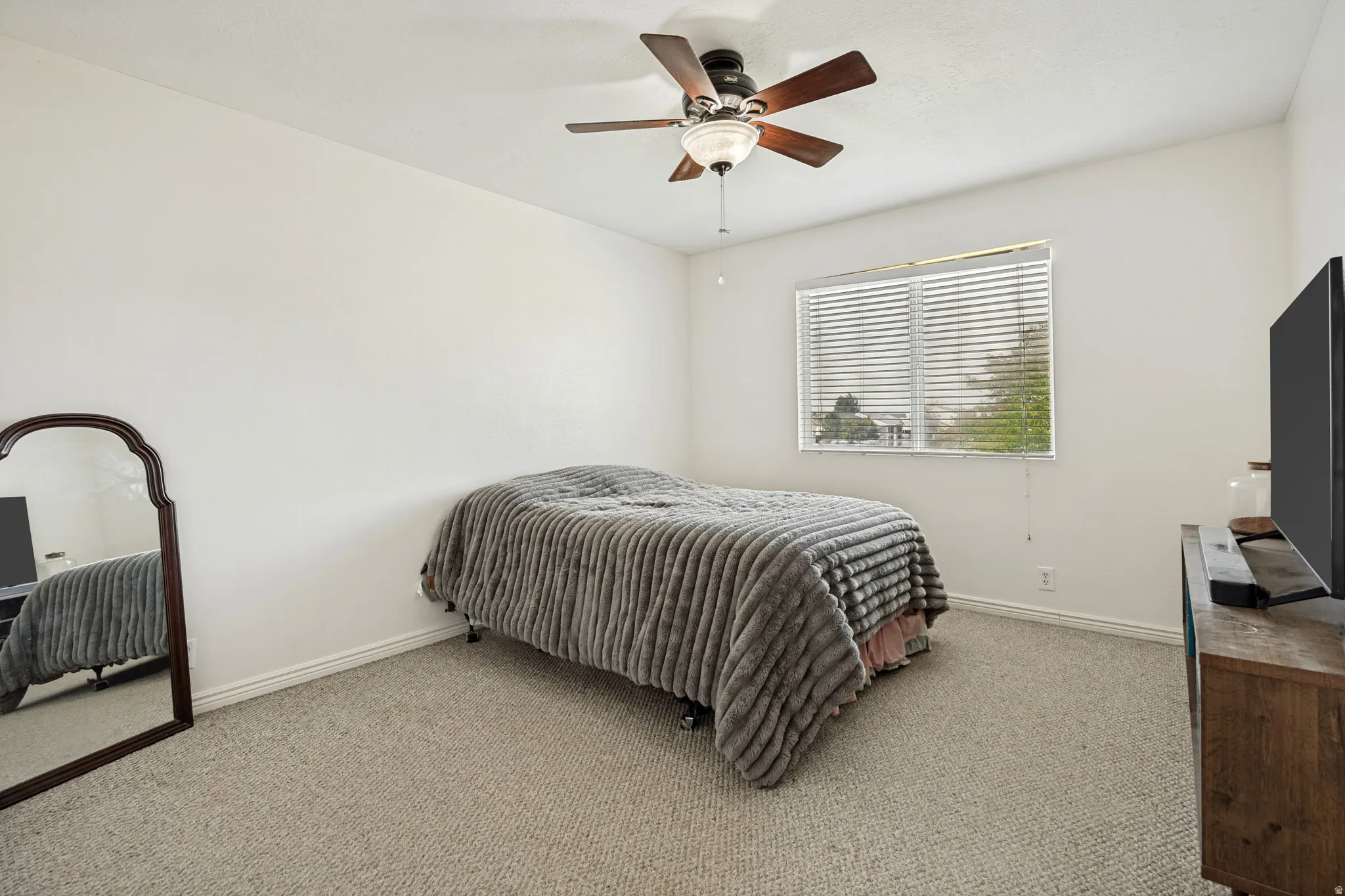 Carpeted room featuring a ceiling fan with integrated lighting, a window with horizontal blinds, and clean white walls