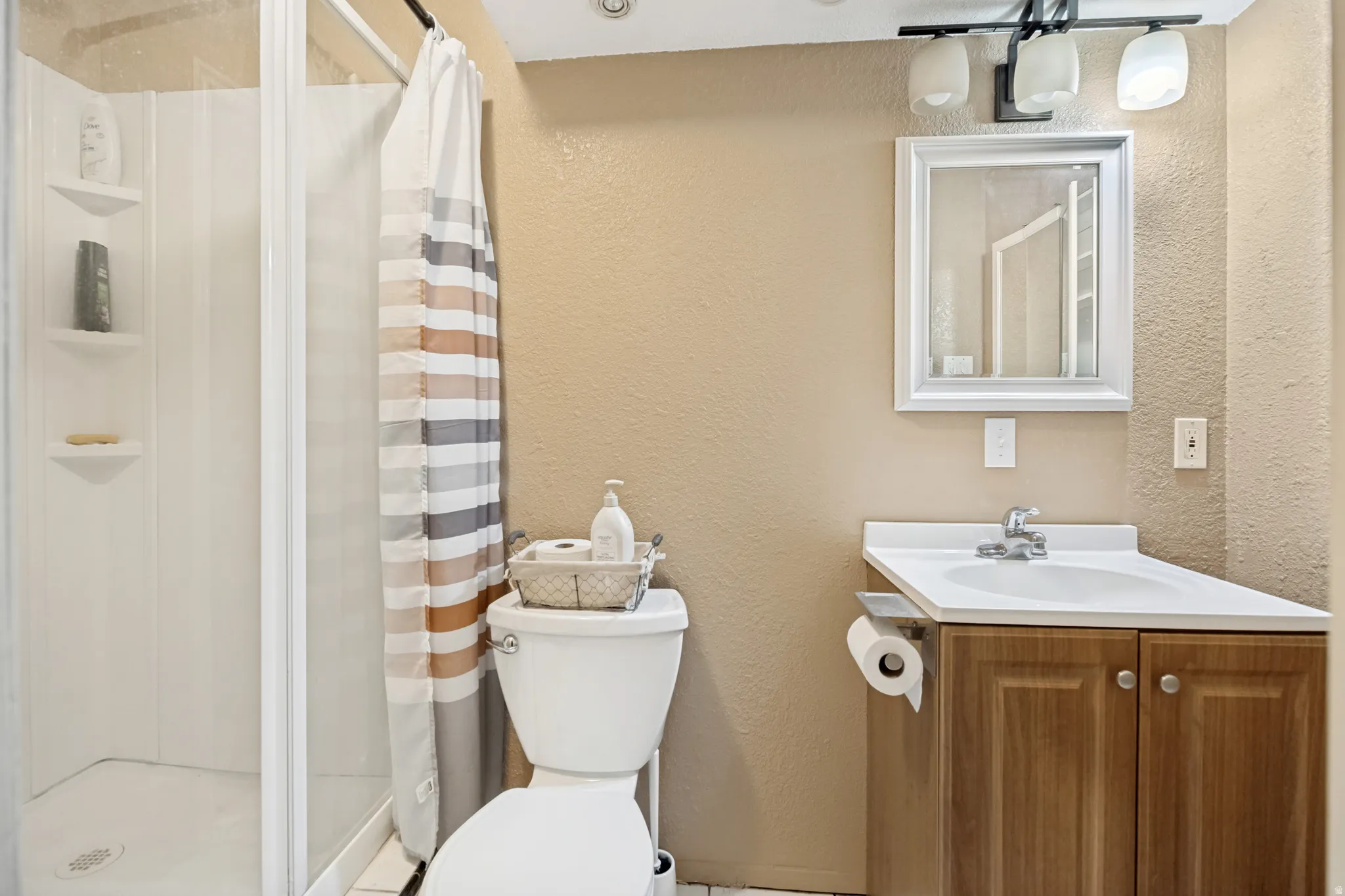 Bathroom featuring a clear glass shower enclosure, a white vanity with a laminate countertop, and a wood-finish cabinet