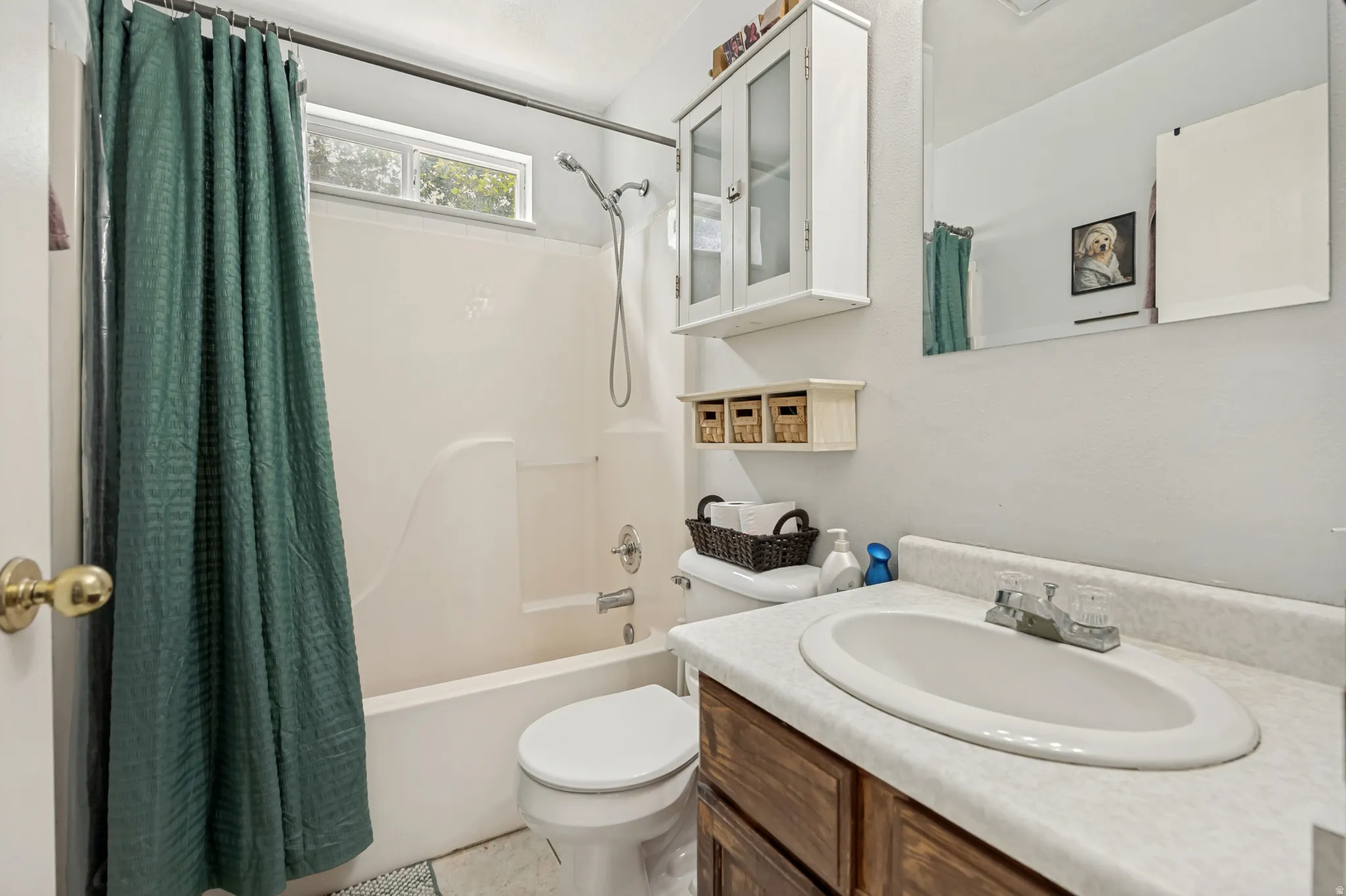 Full bathroom featuring a single vanity with wood-finish cabinetry, a toilet, and a combined tub and shower