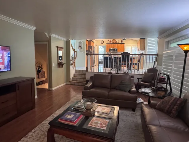 Living area featuring wood-finish flooring, crown molding, and plantation shutters