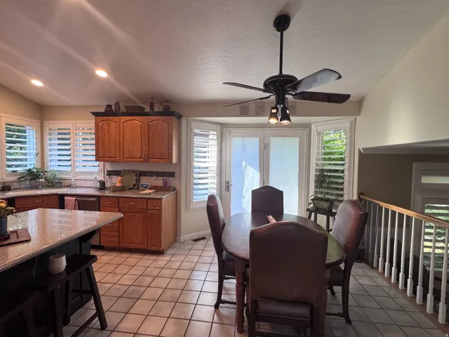 Kitchen and dining area featuring wood-finish cabinetry, granite-style countertops, and white plantation shutters
