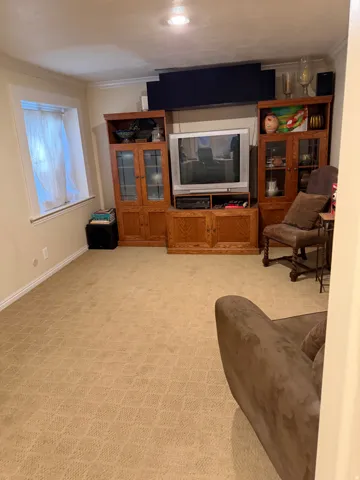 Recessed lighting illuminates a spacious room featuring wall-to-wall patterned carpeting