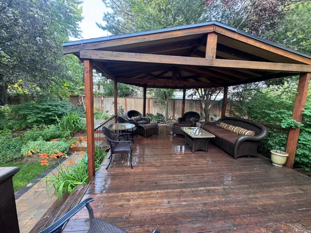 Spacious outdoor deck featuring a wooden gazebo, dark wood flooring, and a black metal railing
