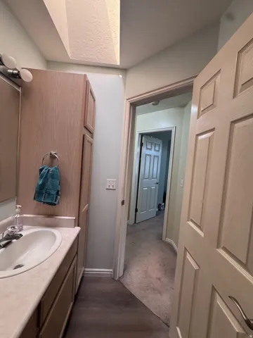 Bathroom vanity with integrated sink, light wood-finish cabinetry, and overhead lighting