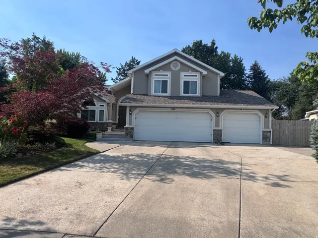 Exterior featuring a stucco facade with stone accents, a multi-car concrete driveway, a two-car garage, and a single-car garage