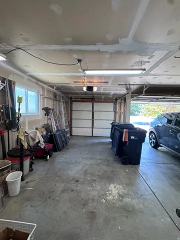 Concrete floor garage with a segmented overhead door and an automatic opener