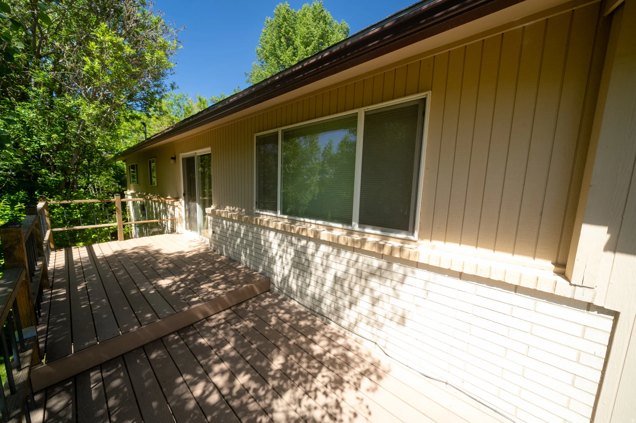 Expansive wood-finish deck with a wood railing and mature trees surrounding
