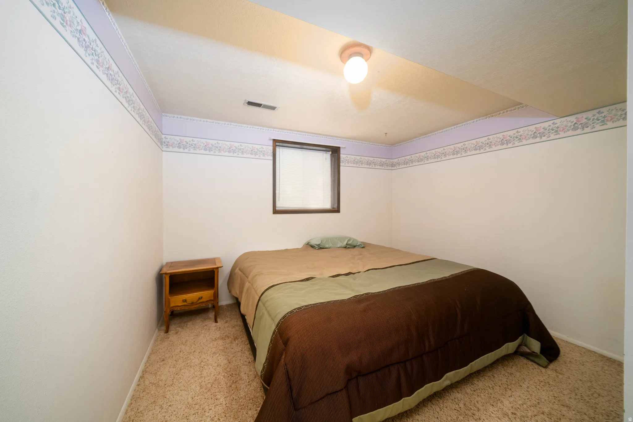 Carpeted room featuring a single window with dark wood trim