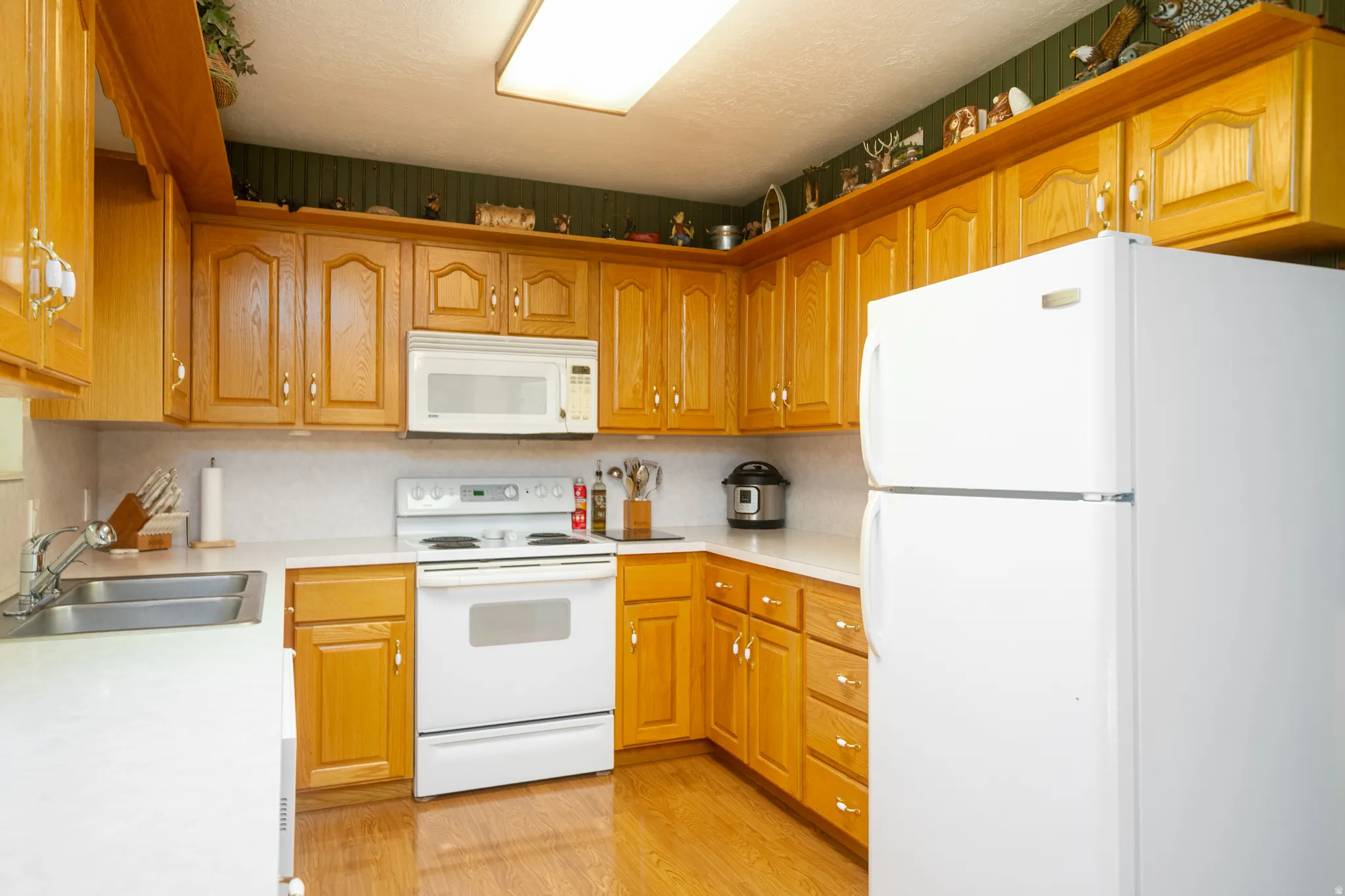 Kitchen featuring abundant wood cabinetry, white countertops, built-in microwave, white electric range, and wood-finish flooring