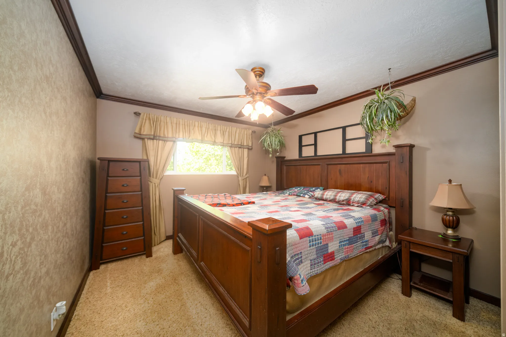 Bedroom featuring textured wallpaper accents, a ceiling fan with integrated lighting, window with drapes and valance, crown molding, and carpeted flooring