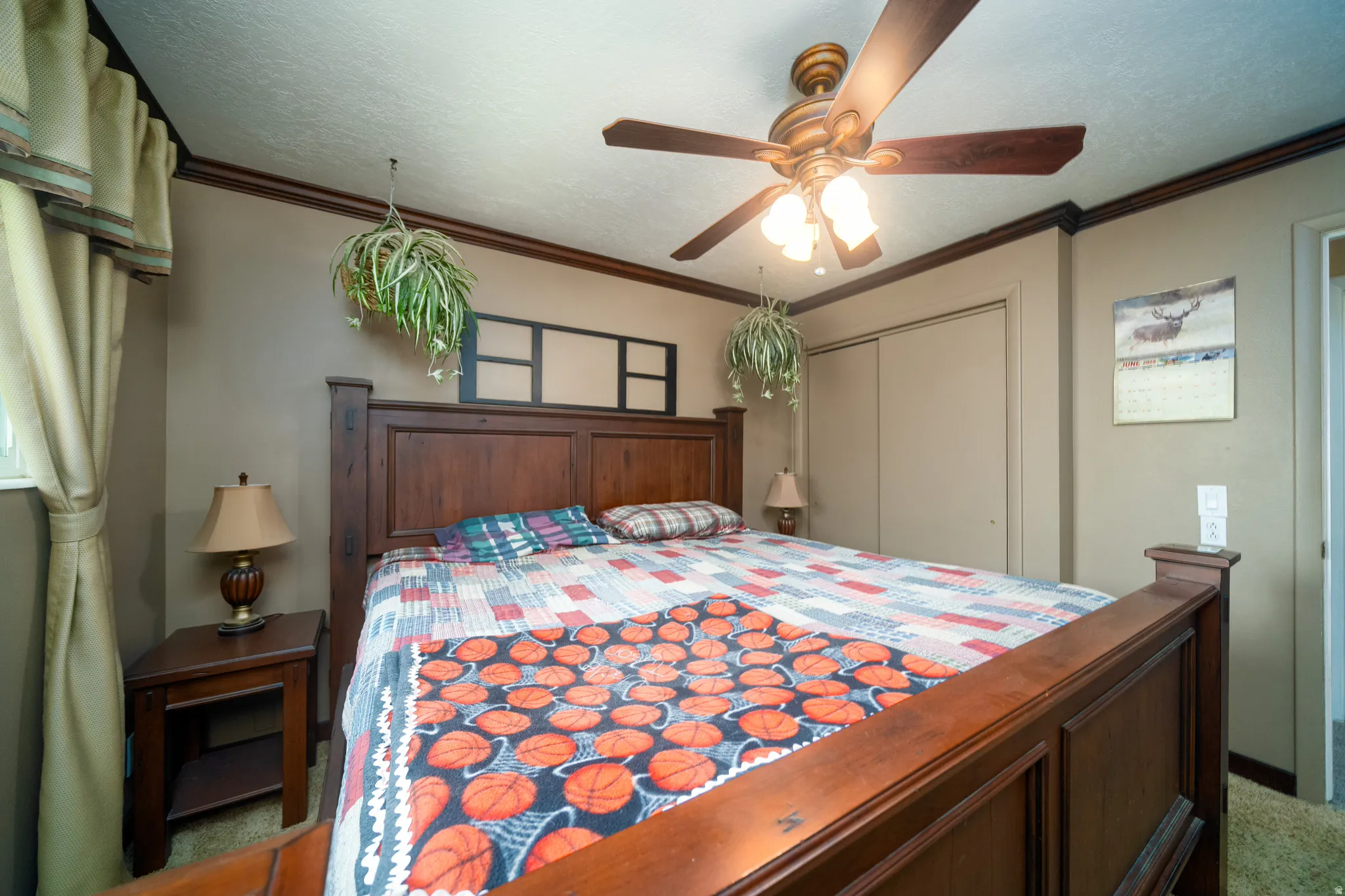 Bedroom featuring a wood-finish bed frame, ceiling fan with integrated lighting, and a window with drapes