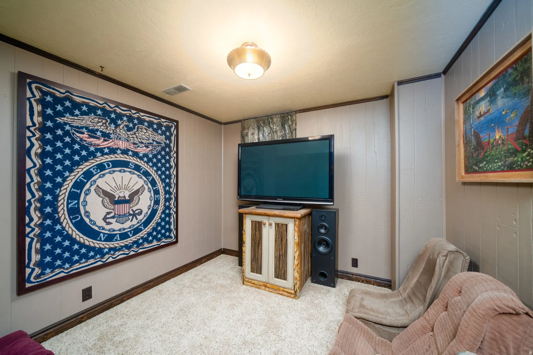 Carpeted room featuring vertical wall paneling, crown molding, and a flush mount ceiling light fixture