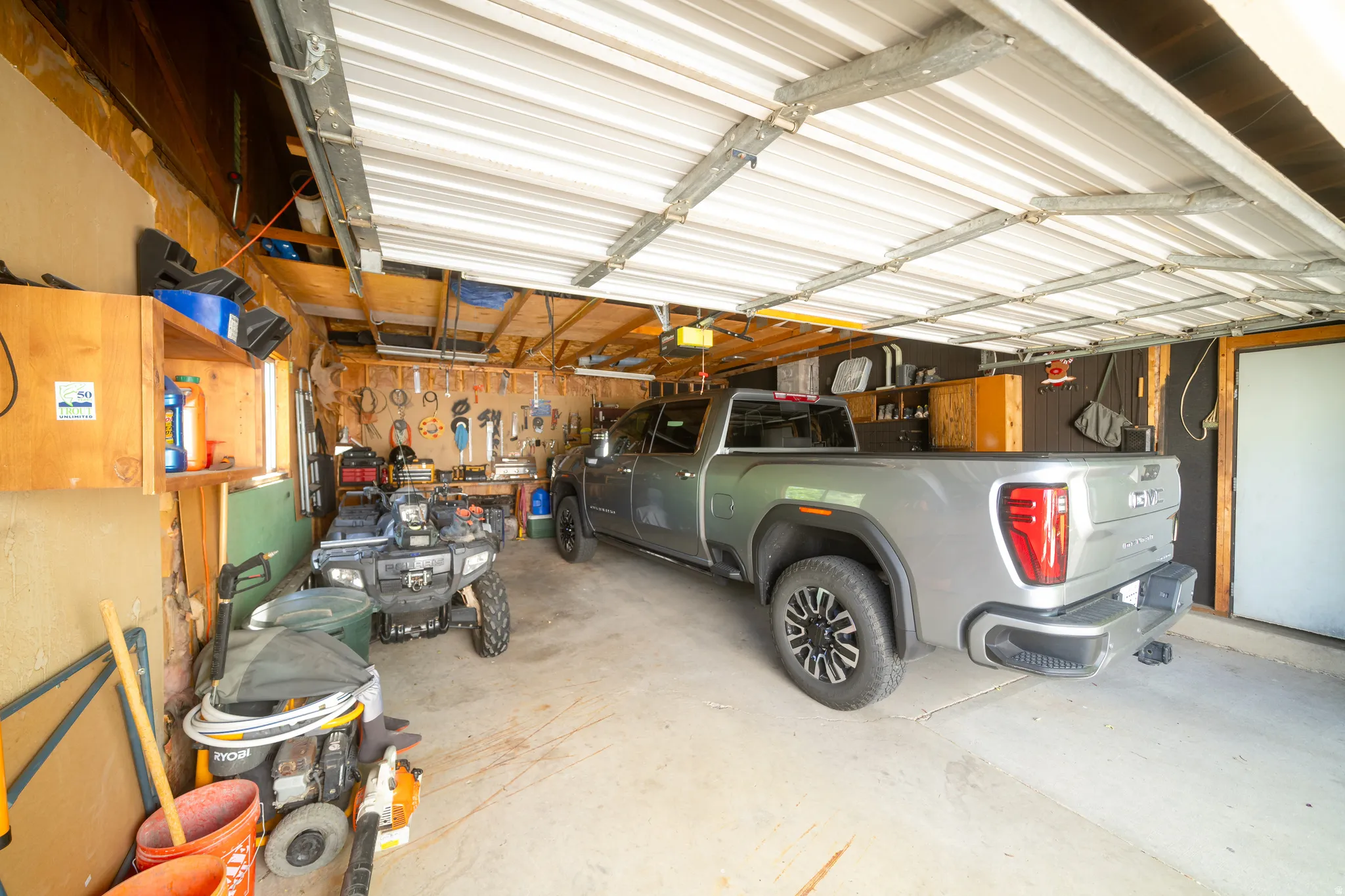 Attached garage with a corrugated metal ceiling and concrete flooring