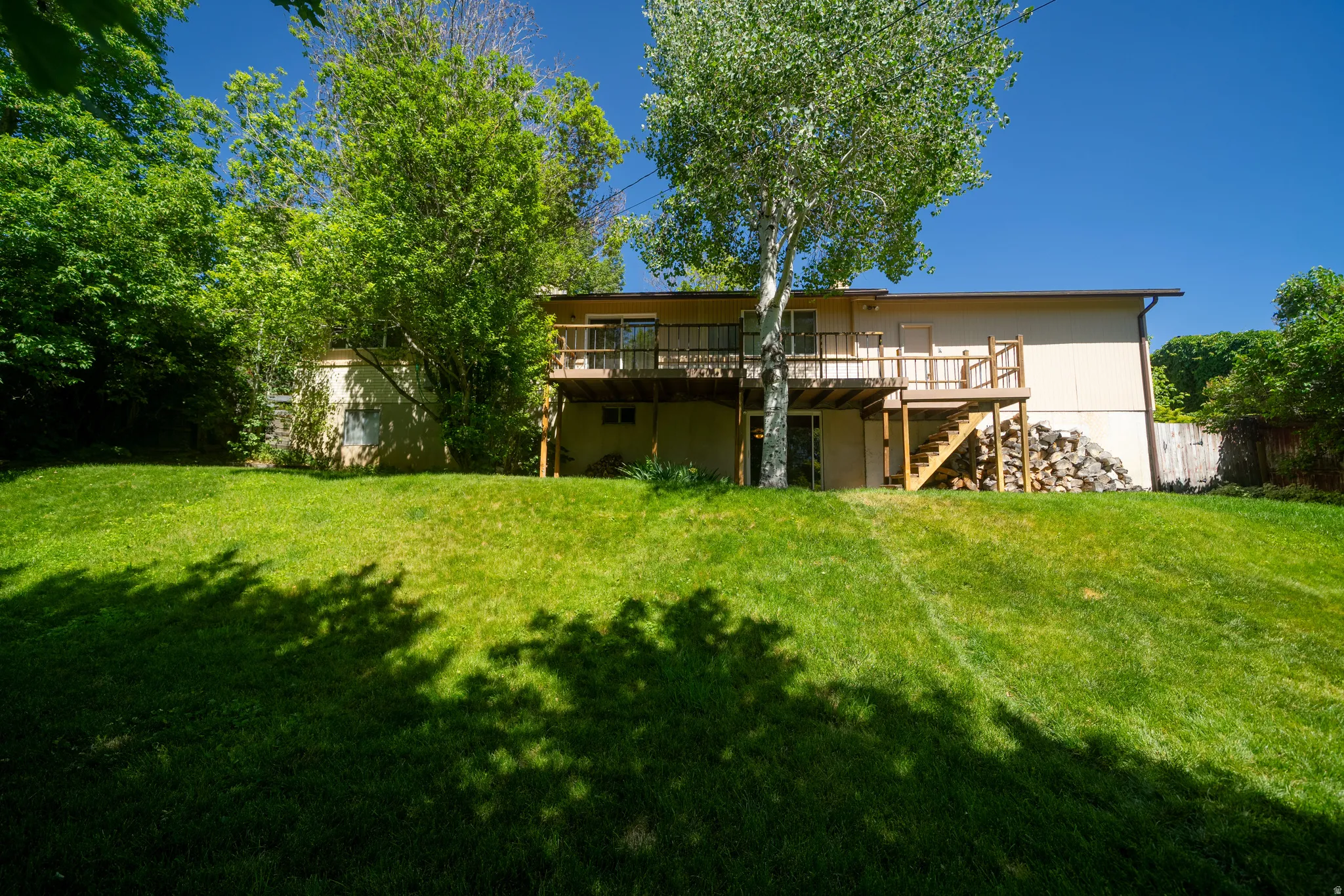 Rear exterior featuring a multi-level wood deck, exterior stairs, and sliding glass doors