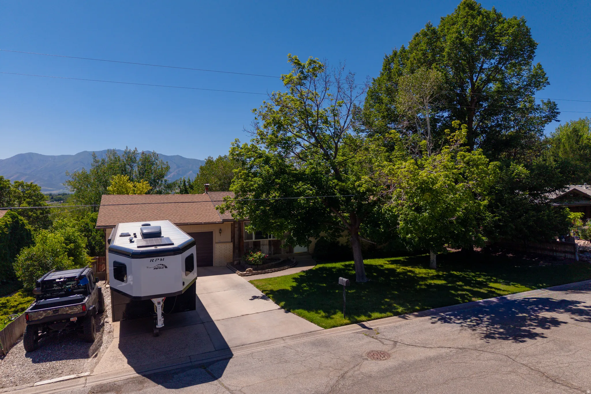 Single-story home featuring a front-facing garage, a concrete driveway, and a gravel parking area