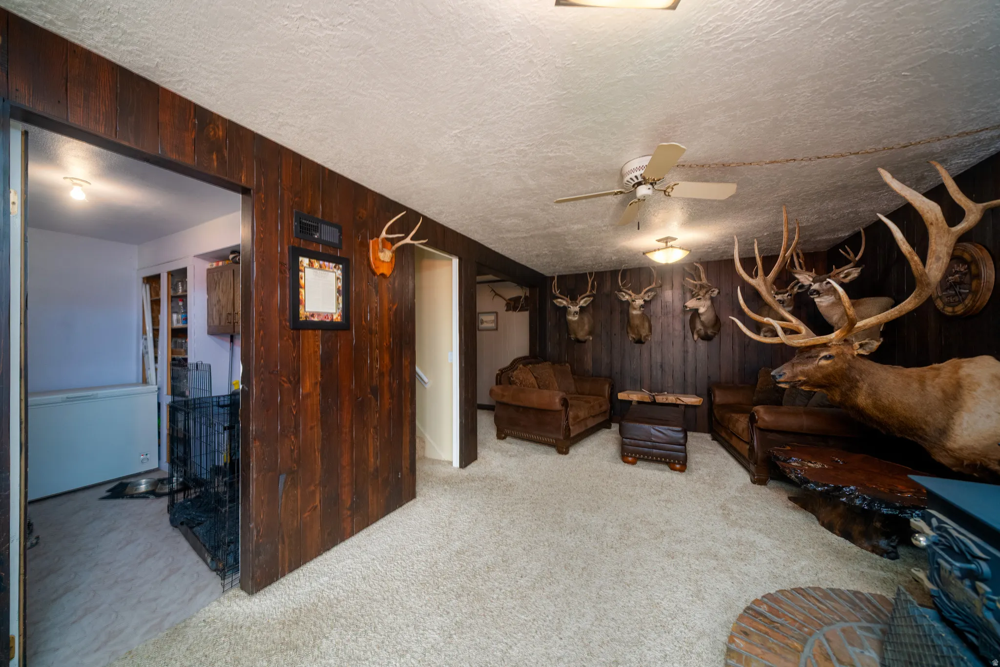 Spacious room featuring rich wood paneling and neutral carpeting