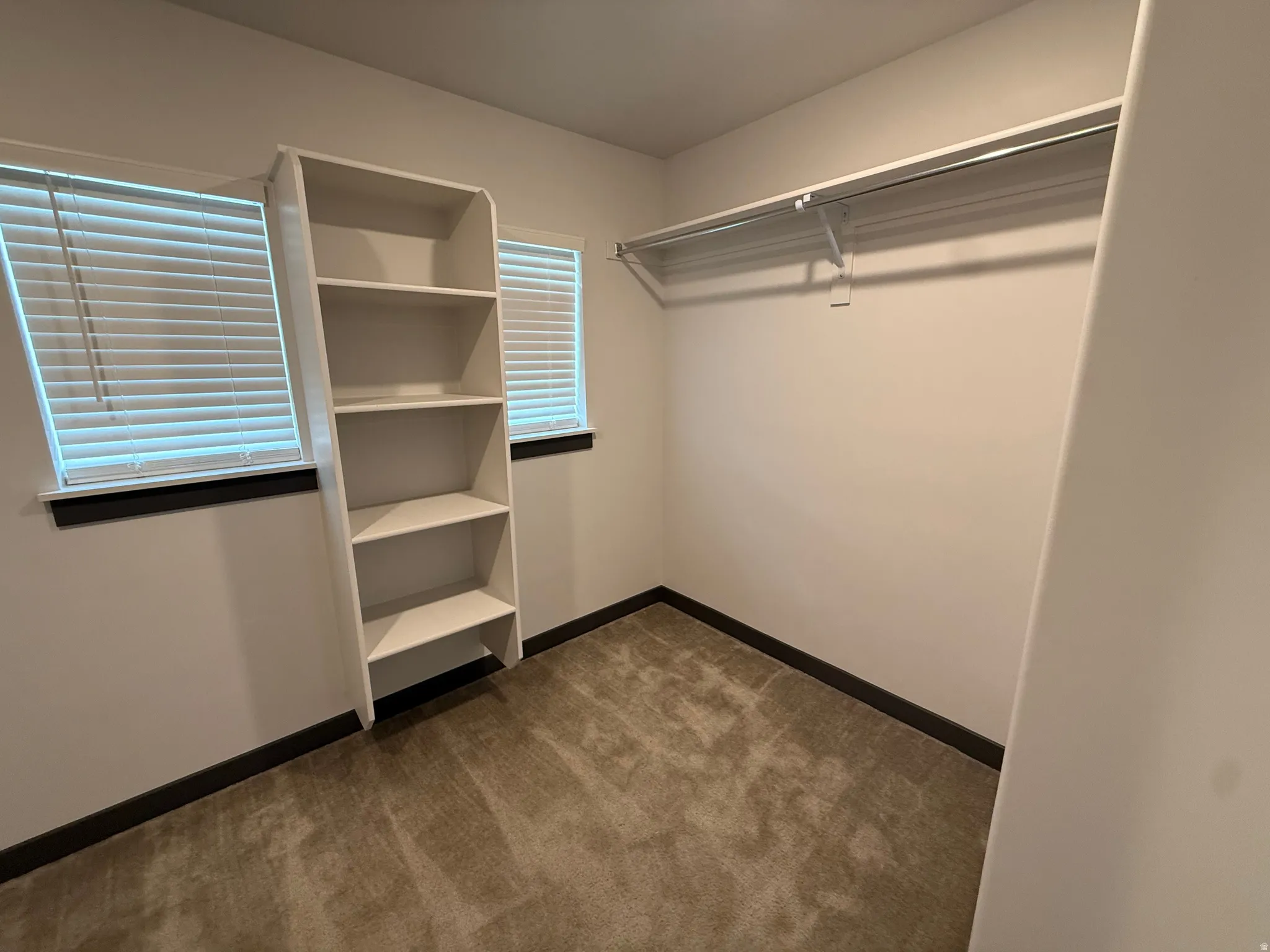 Spacious room featuring neutral carpeting, white walls, and dark trim